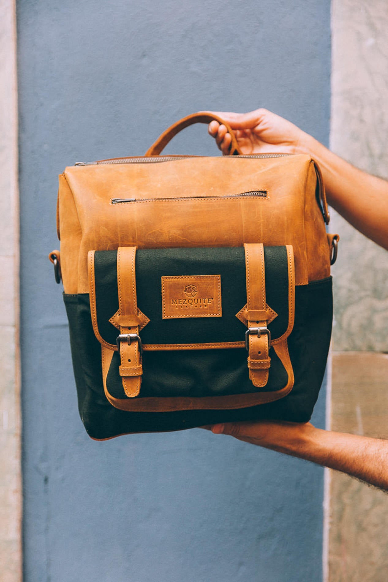 Handcrafted leather and canvas backpack by Mezquite Leather, photographed in a Mexican street — sustainable luxury made to endure between Mexico and Canada.